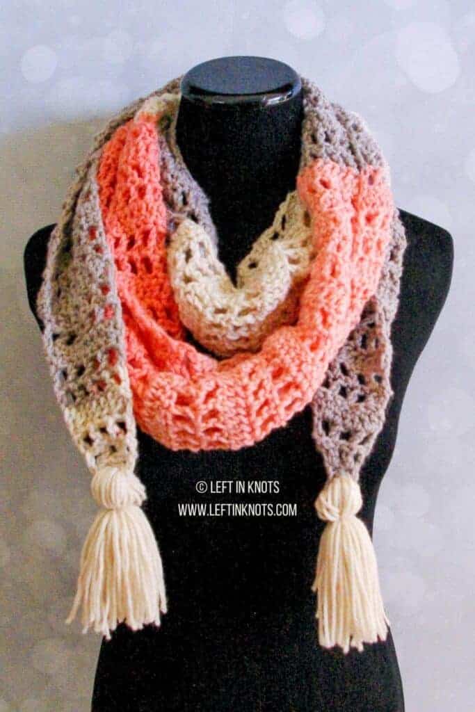 A coral and gray crochet scarf with tassels