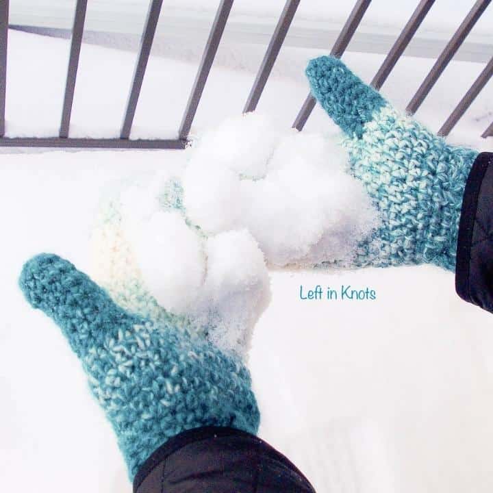 Crochet mittens worn on a woman's hands holding snow