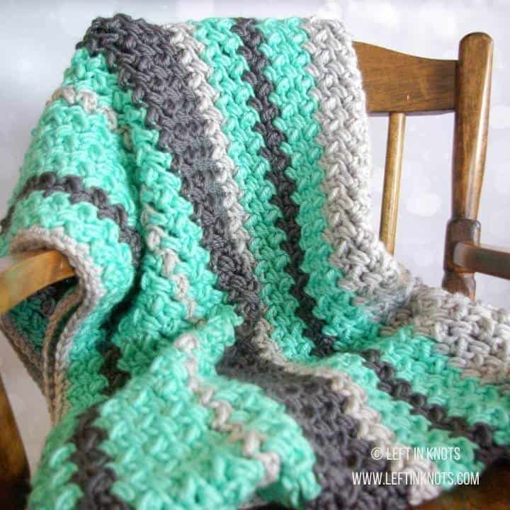 A crochet baby blanket made with chunky yarn and random striping