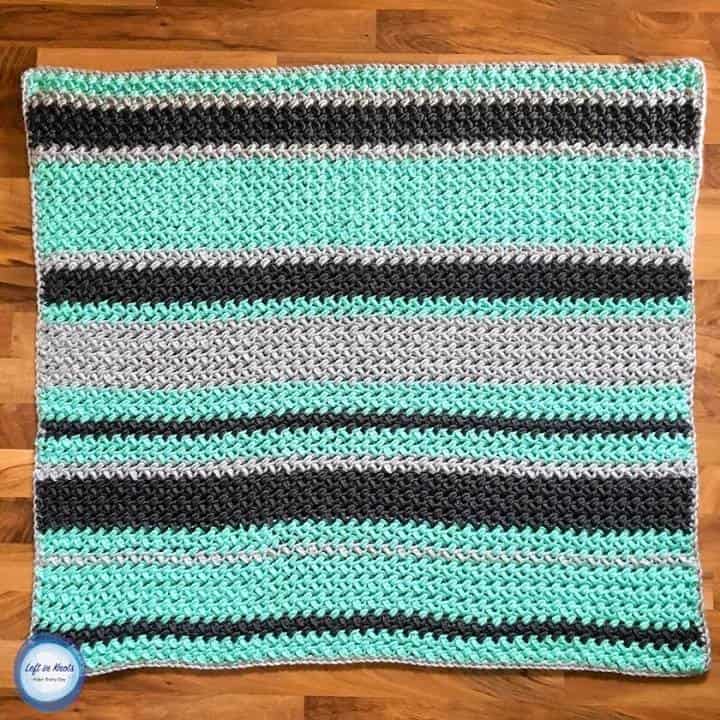 A gender neutral crochet baby blanket made with chunky yarn and random striping