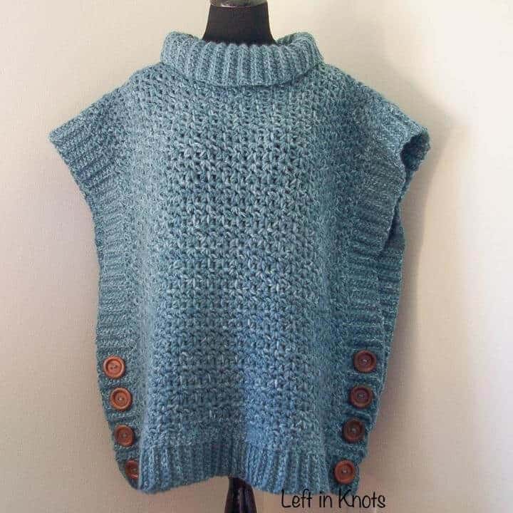 A blue crochet poncho sweater accented with brown buttons