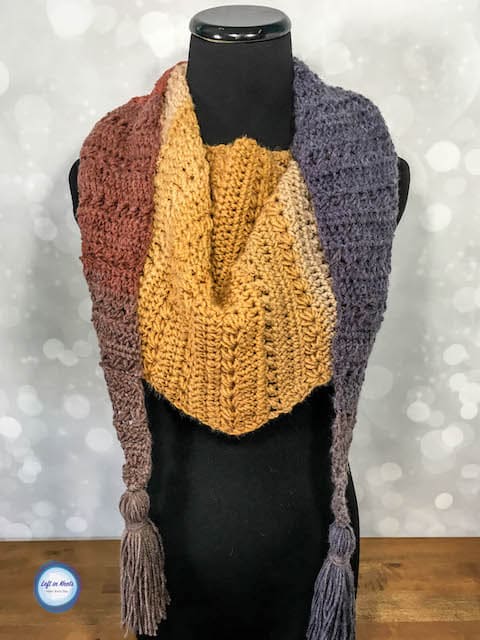 A modern crochet triangle scarf made with textured stitches and tassels
