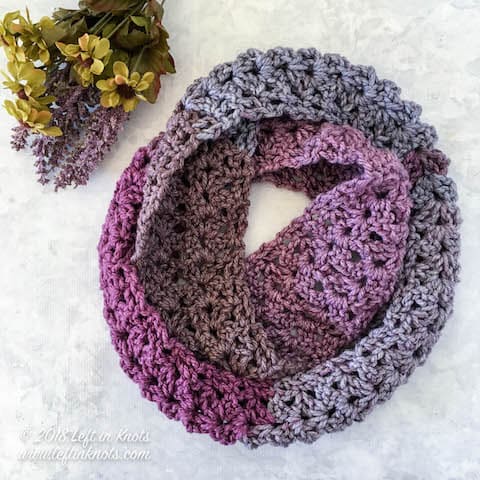 A purple chunky crochet infinity scarf made with the iris stitch