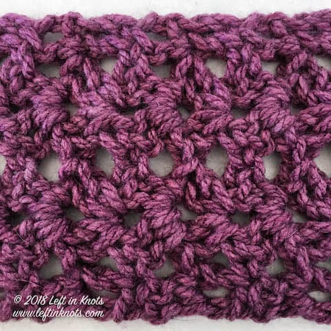 A purple chunky crochet infinity scarf made with the iris stitch