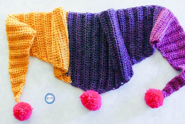 A crochet triangle scarf for kids with pom poms