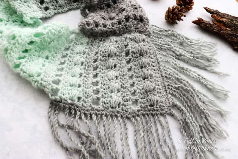 A gray and mint bandana style crochet cowl with fringe
