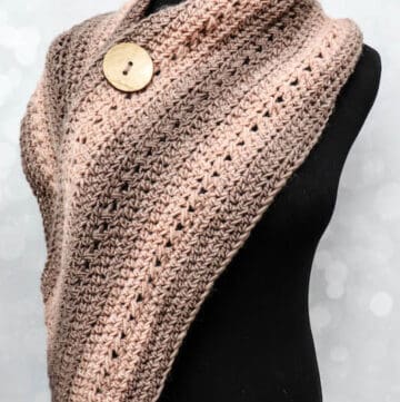 A wide crochet wrap scarf with button