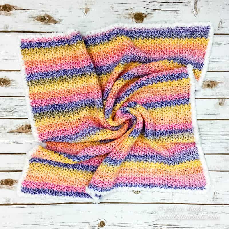 An easy striped crochet baby blanket with a white fuzzy border