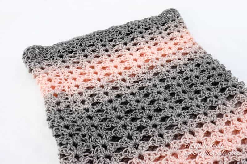 A pink and gray crochet cowl using the iris stitch