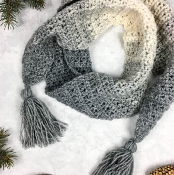 A gray and cream scarf with angled edges and tassels