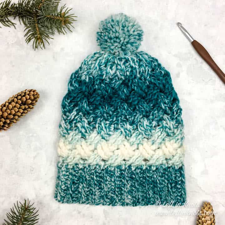 A teal and cream crochet beanie made with the Celtic Weave stitch