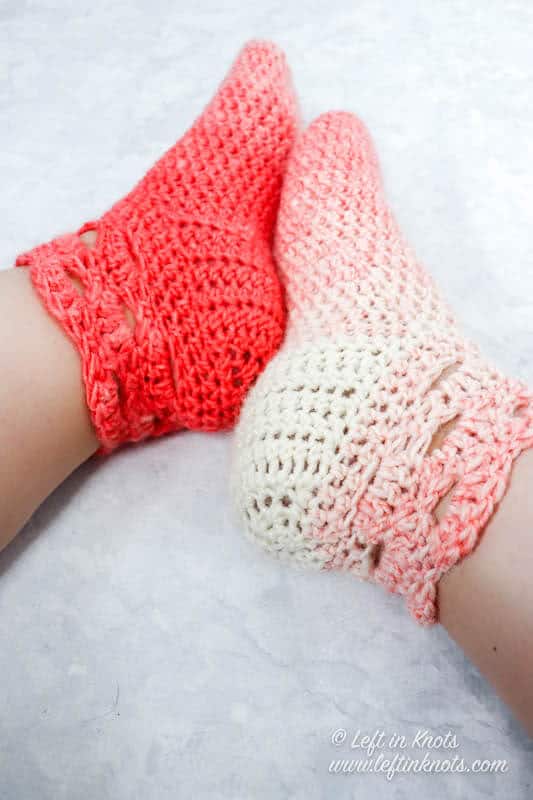 A pair of coral and cream crochet slipper socks made with the arcade stitch