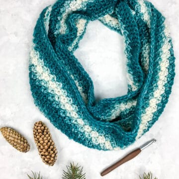 A teal and cream crochet infinity scarf made with the lemon peel stitch