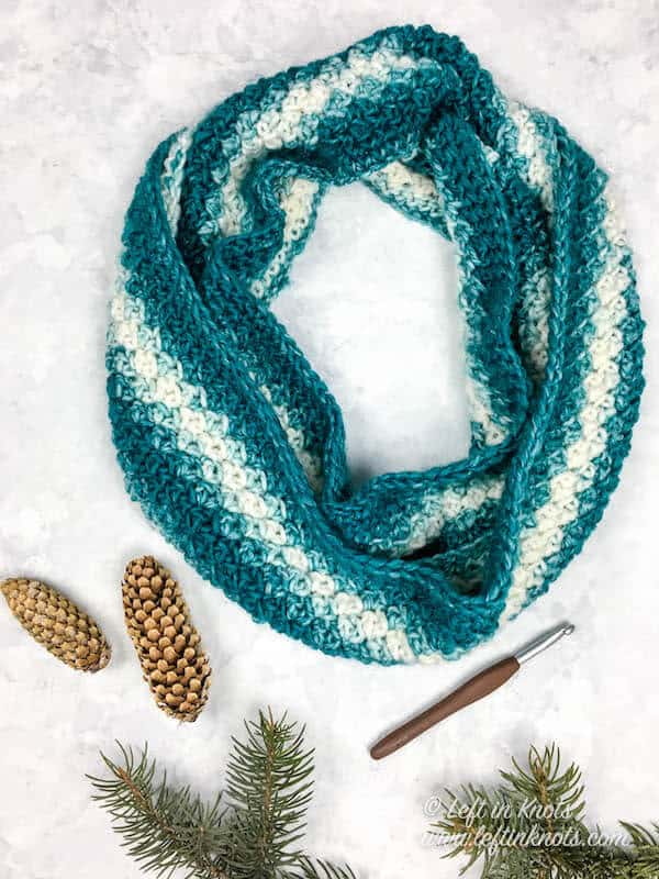 A teal and cream crochet infinity scarf made with the lemon peel stitch