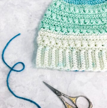 A crochet messy bun beanie made with the star stitch