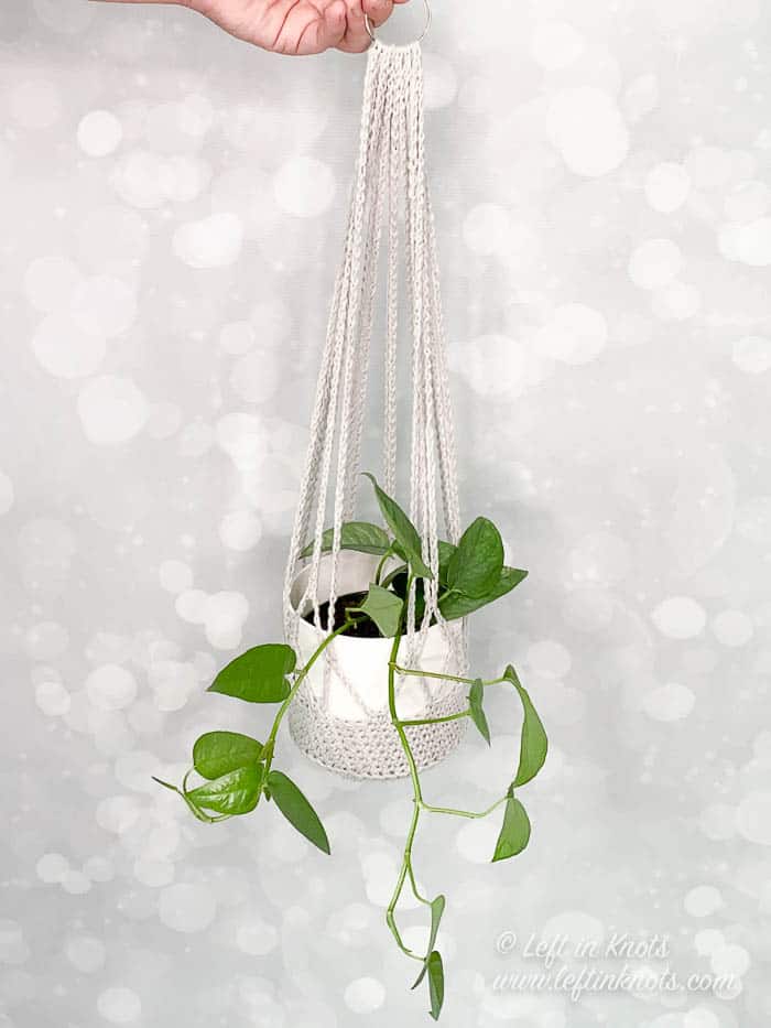 A gray crochet plant hanger made with cotton yarn