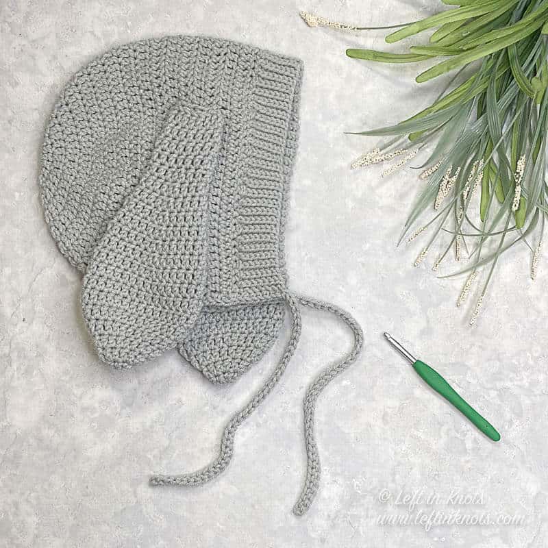 A crochet bunny bonnet made with gray yarn in an adult size