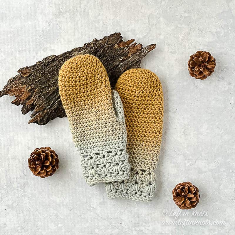 Gold and ice blue crocheted mittens shown worn on a hand