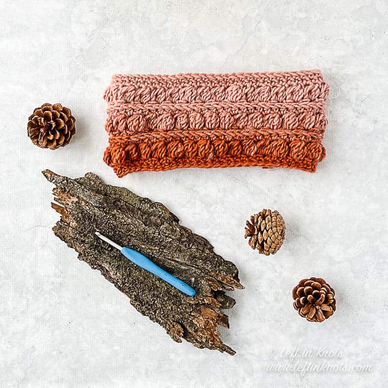 A crocheted ear warmer made with the bobble stitch in orange and pink yarn