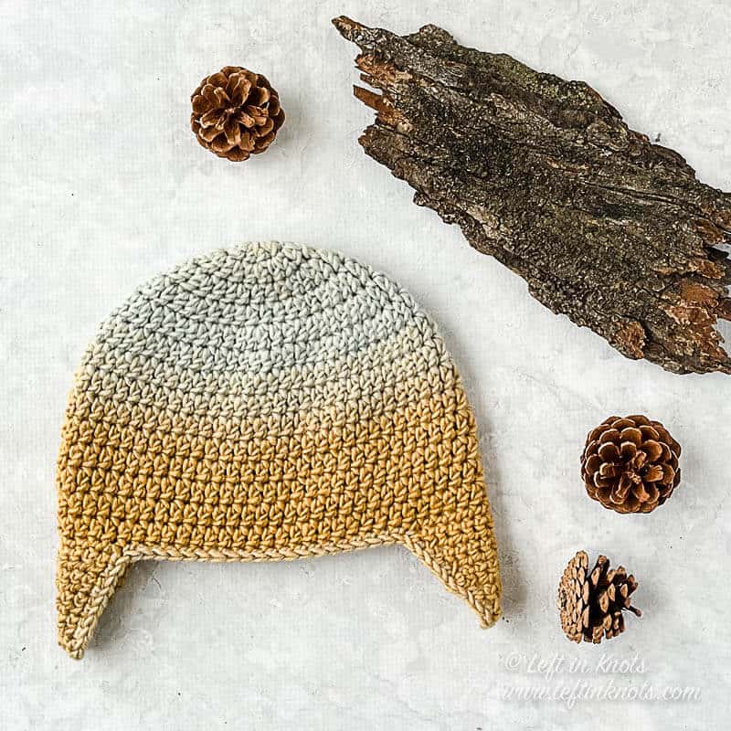 A gold and blue crochet beanie with earflaps