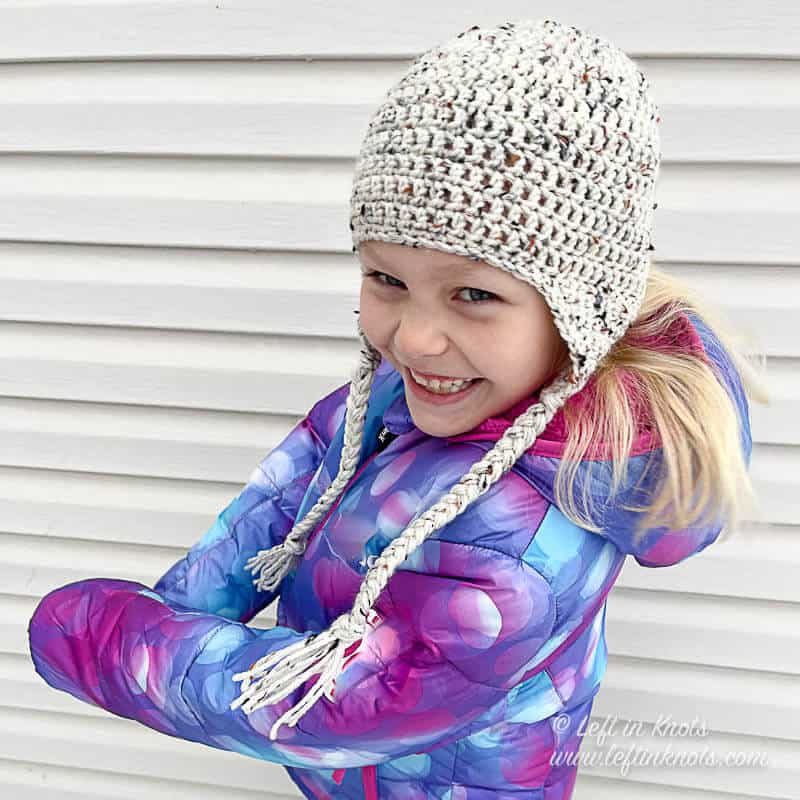 A young blonde girl wearing a crocheted hat